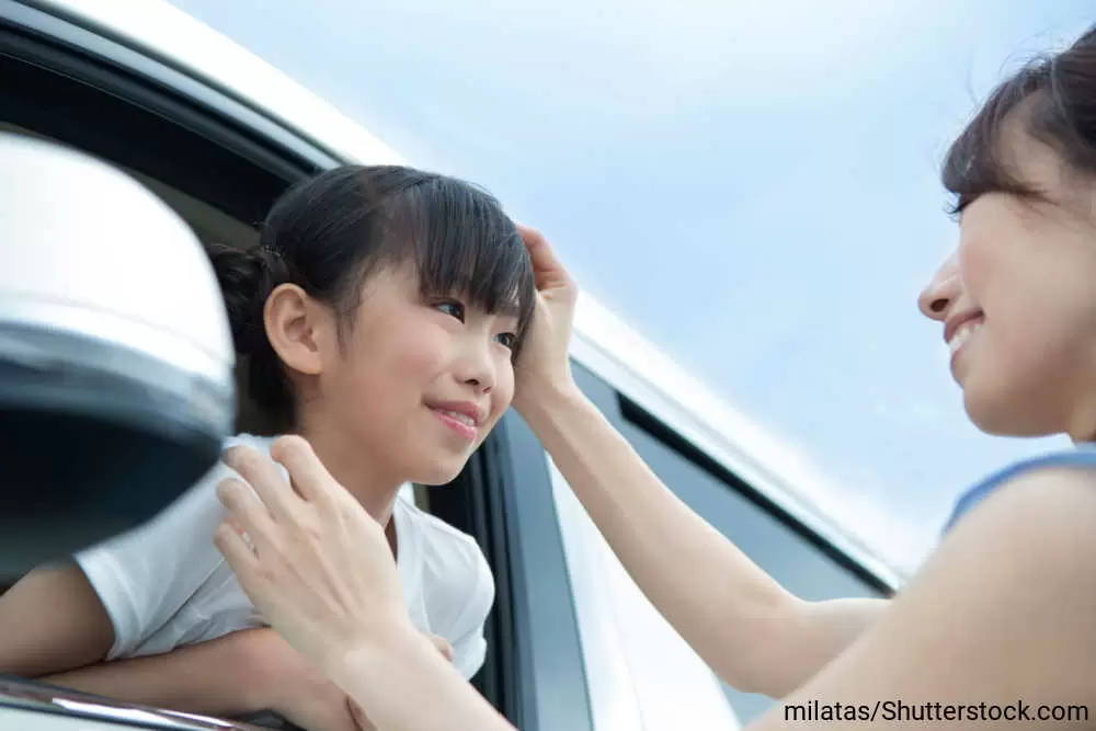 車に乗った女の子と、見送る母親