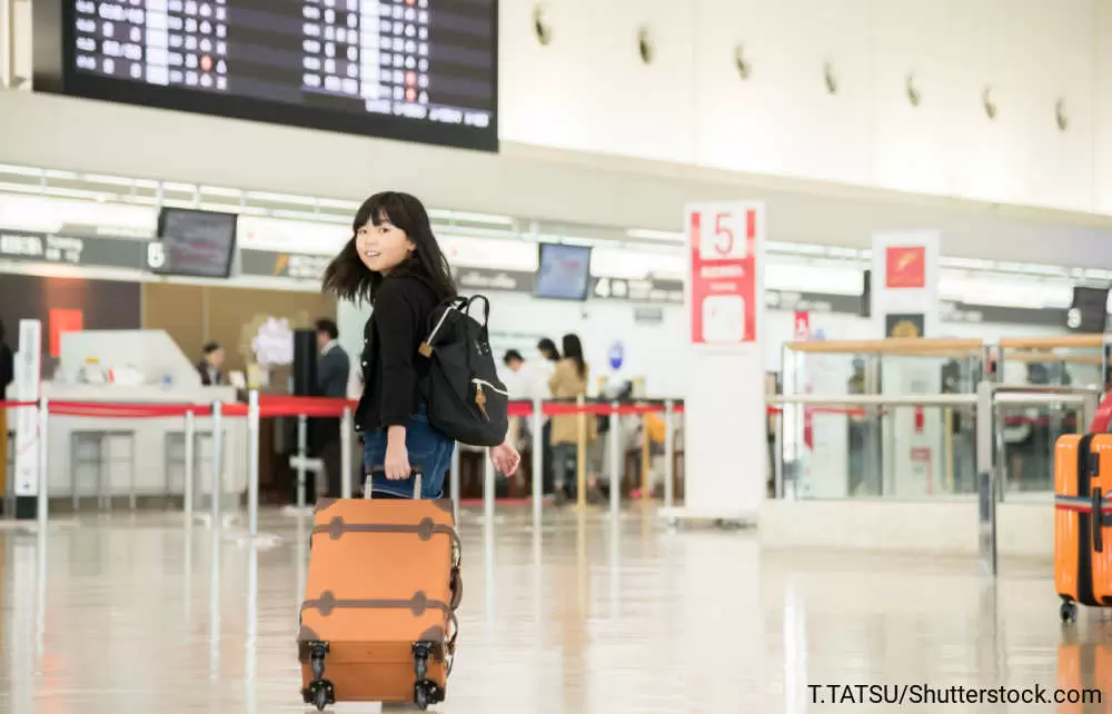 空港でキャリーバッグを引いている女の子