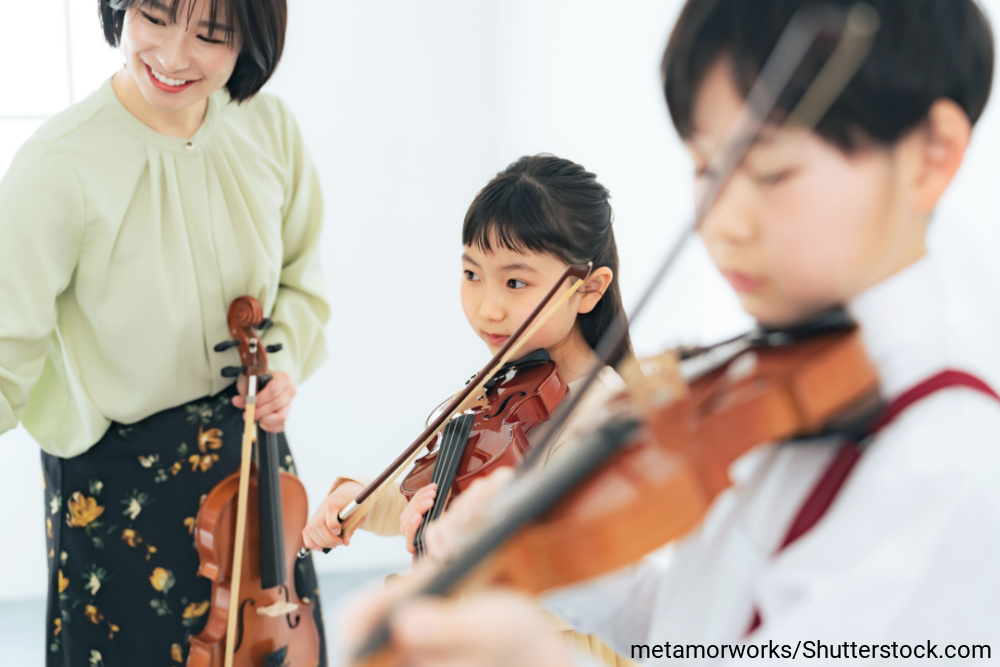 女性の先生からバイオリンを習う女の子と男の子
