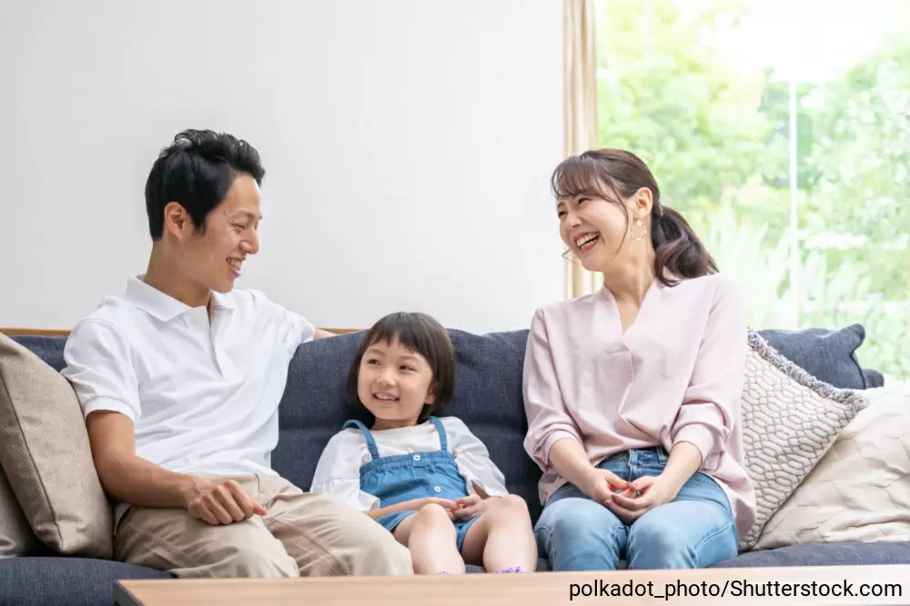 ソファーに座って楽しそうに笑う女の子と両親