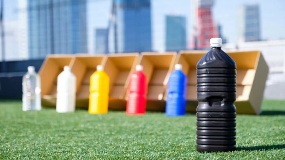 透明なペットボトルと、白・黄色・赤・青・黒それぞれに色を塗ったペットボトルに水を入れて、太陽に当てているところ