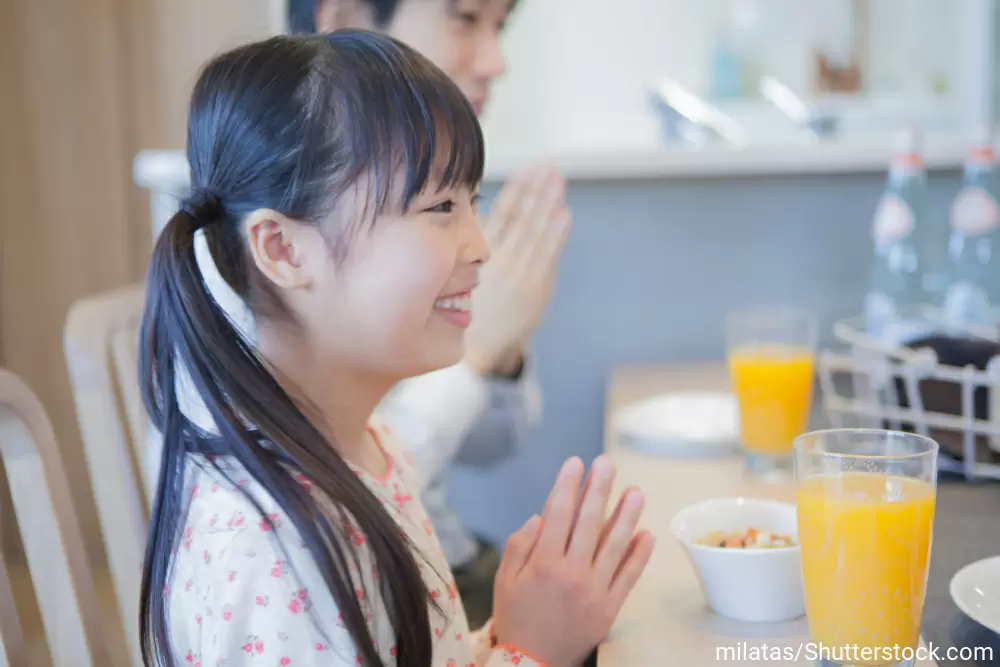 手を合わせて「いただきます」のあいさつをしている女の子