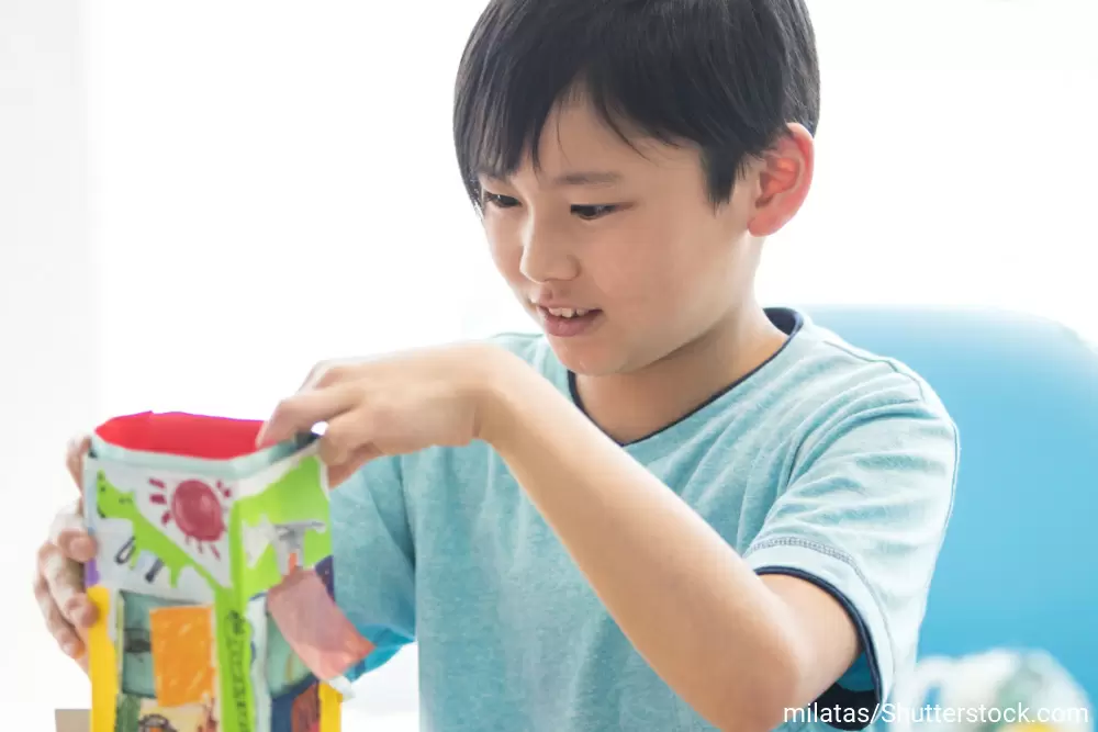 紙でできた家のようなもので遊ぶ男の子