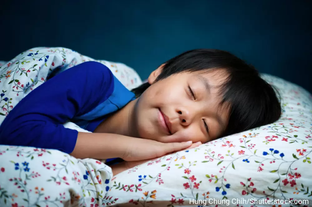 布団の上で気持ち良さそうに寝ている小学生くらいの男の子