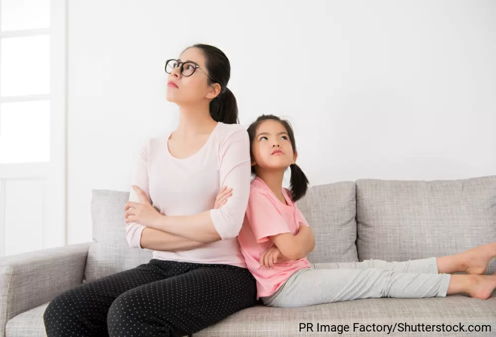 ソファの上で腕組みをして、お互い別の方向を見てケンカしている様子の母と娘