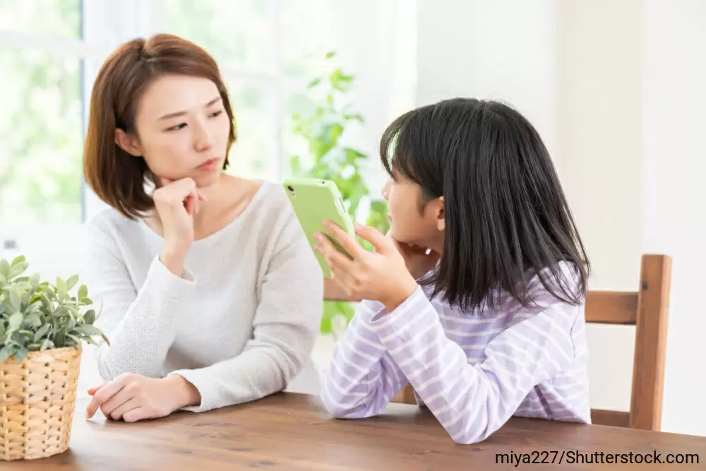 テーブルに肘をついて、娘の話に耳を傾けている母親