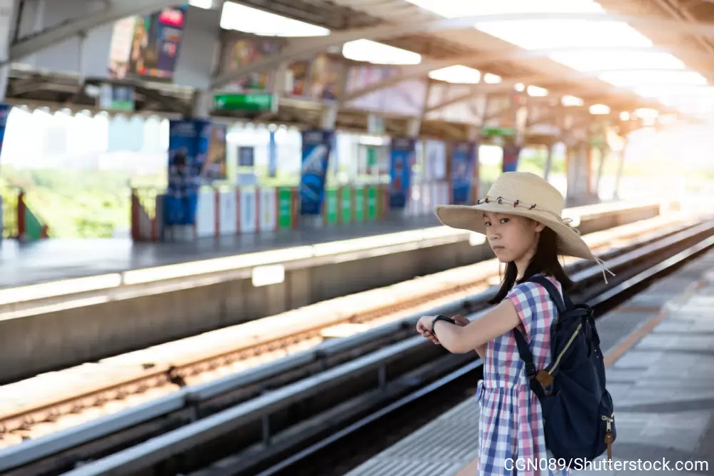 ホームで腕時計を片手に電車を待っている女の子