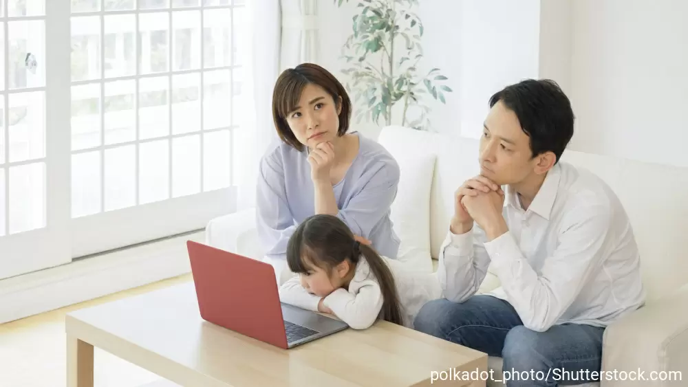 パソコンの前で悩んでいる様子の夫婦と女の子
