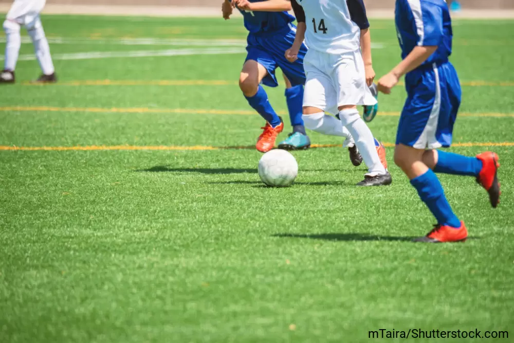 サッカーコートの中でボールを追いかけている男の子たち