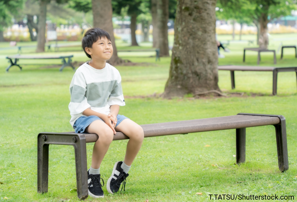 公園のベンチに座って、上を向いてボーっとしている男の子