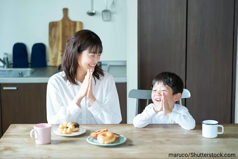 おやつと飲み物を前にテーブルにつくお母さんと男の子