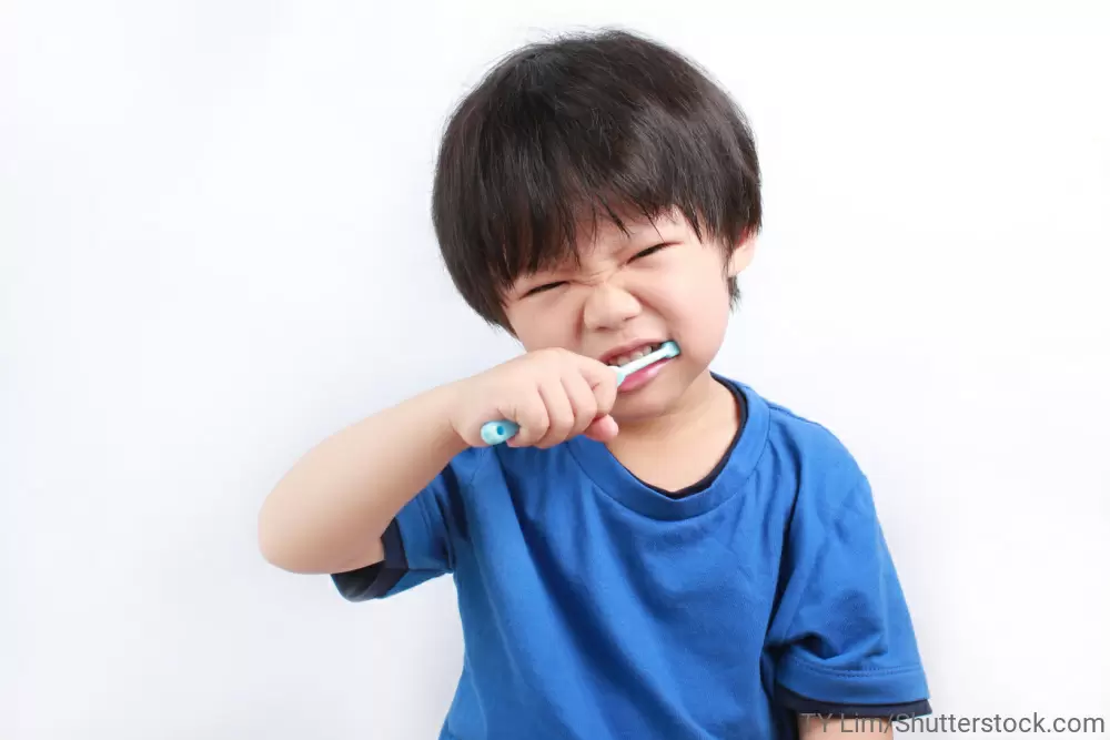 顔をしかめて歯磨きをしている男の子