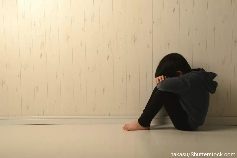 膝を抱えてふさぎ込んでいる男の子