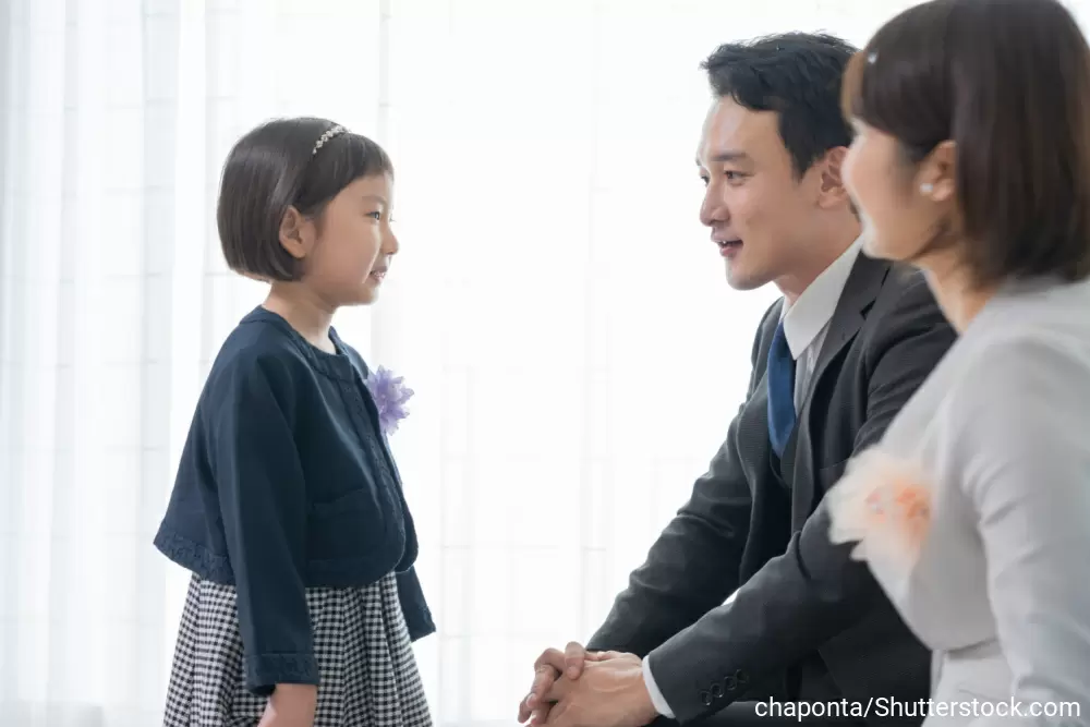 正装をしてこれから入学式に行く様子の女の子と両親