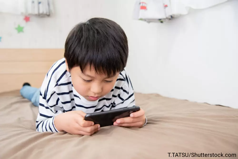ベッドに寝っ転がってゲームをしている男の子
