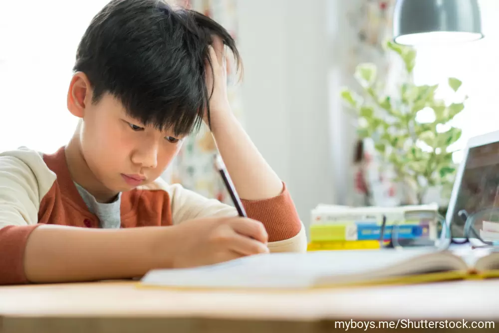 机に向かって、考えながら問題を解いている男の子