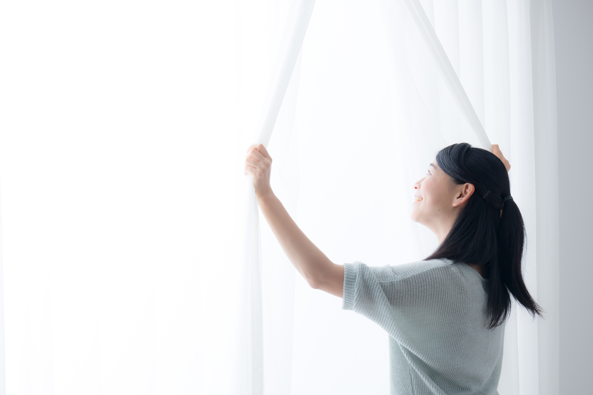 カーテンを開ける女性