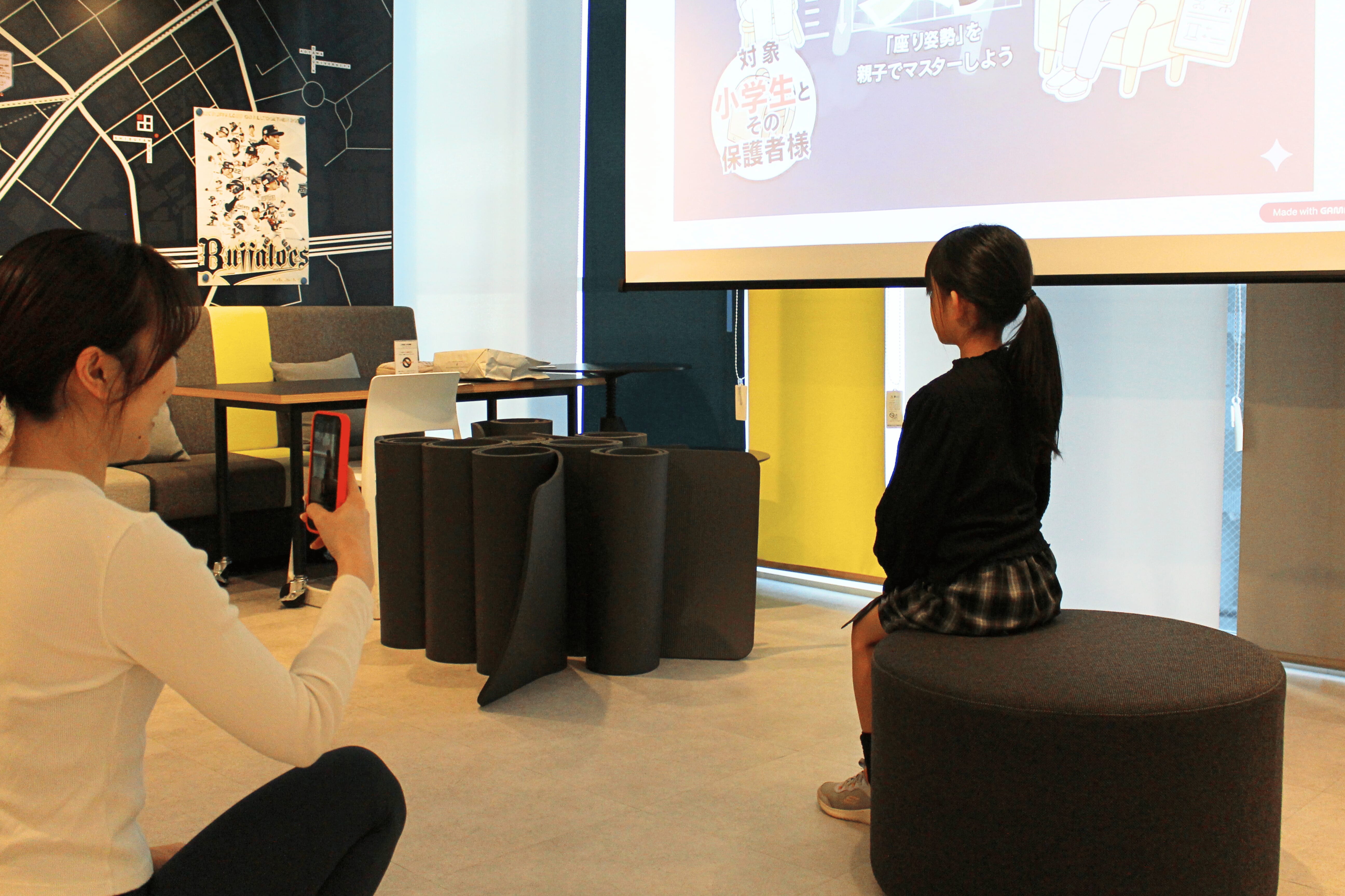 子どもの座る姿勢をスマホで撮影する保護者