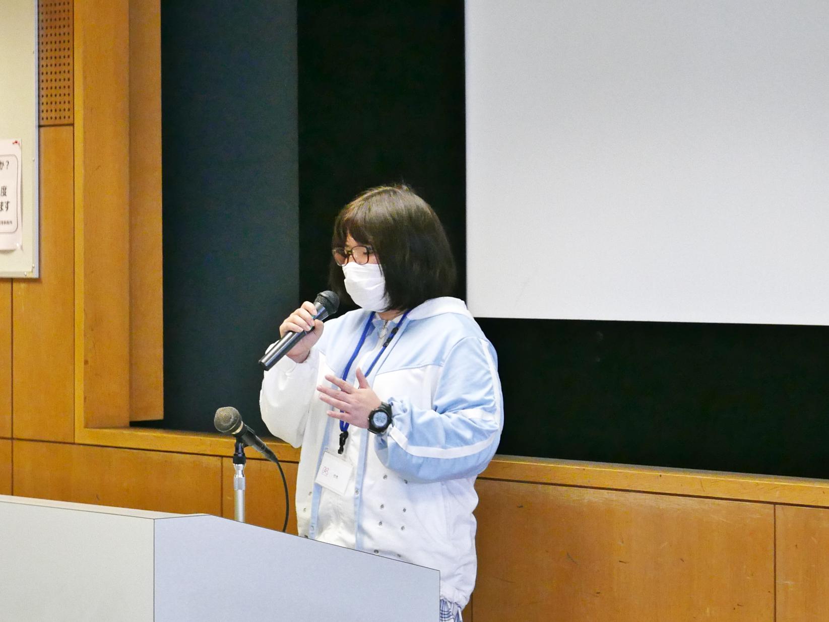 前に出てマイクを持って話す卒業生の女性