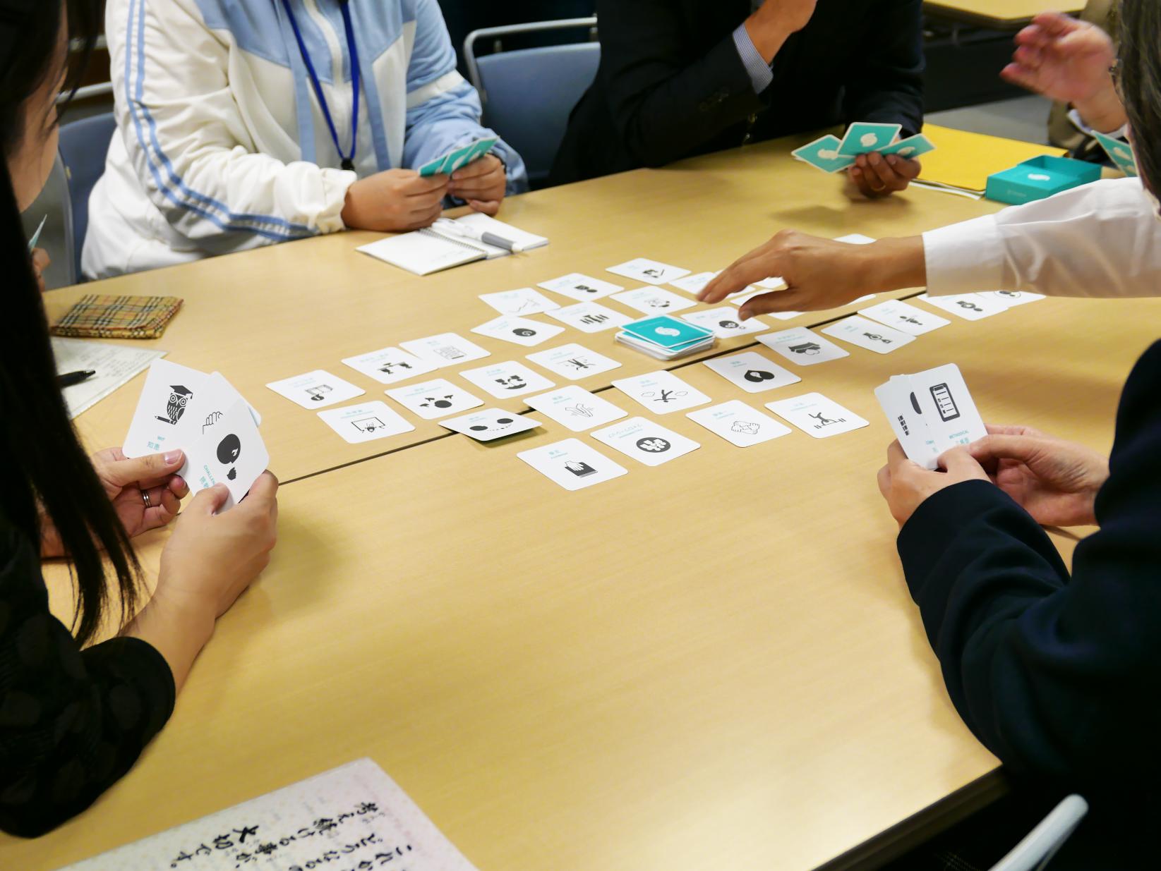 「遊び心」「仕事」「協力」などさまざまな単語が書かれたカードでゲームをする人々