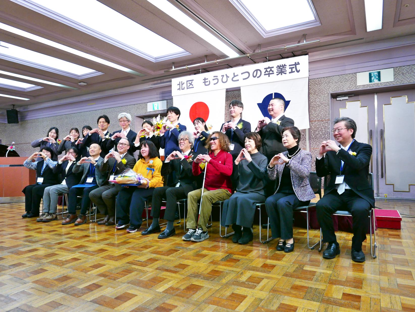 卒業生を囲んで記念撮影をする職員や関係者