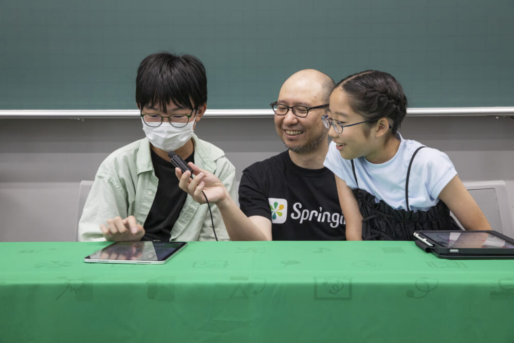 ぱんくぅ選手のゲーム画面を笑顔で覗き込むソユーズ選手