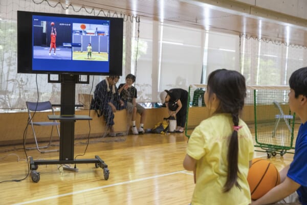 画面に映されたプロのフォームと撮影された自分のフォームを確認する子ども